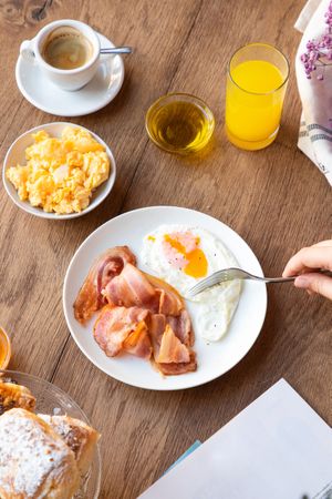 Person reading while eating bacon and eggs at table