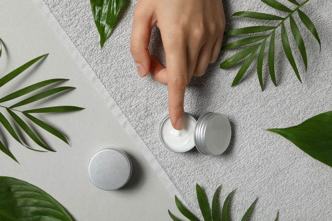 A jar of hand cream with leaves on a light background.