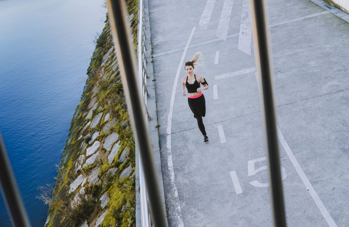 Young woman running on embankment near water