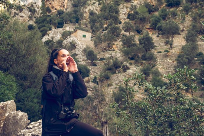 woman backpacker screaming loudly in mountains while ge