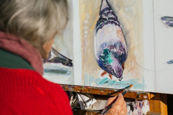 Anonymous woman painting on canvas in garden