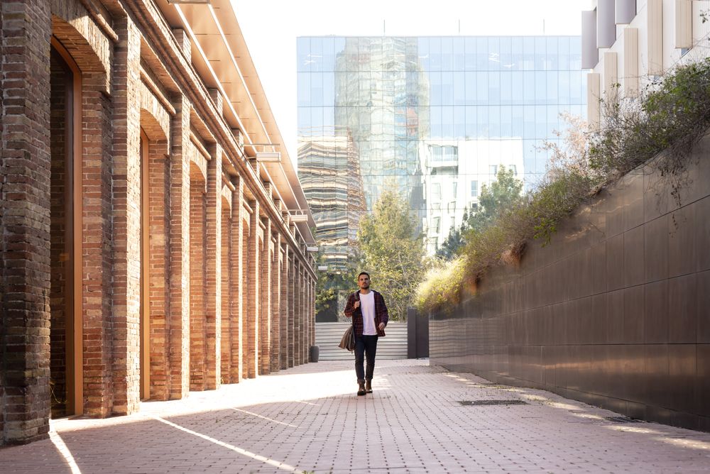 Front view of a man holding shoulder bag walking through the city