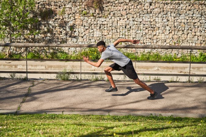 Athletic man running on asphalt path in summer
