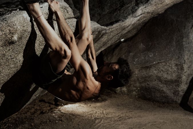 Man practicing rock climbing among large rocks in a forest