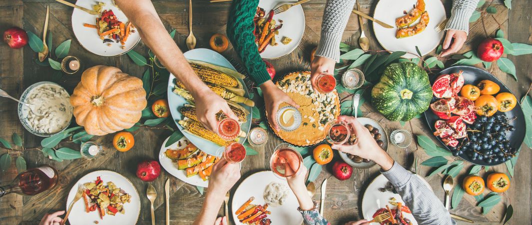 Group of people with wine glasses over festive vegetarian table with pie, wide composition