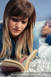 Woman reading a book lying in bed 5pgO68