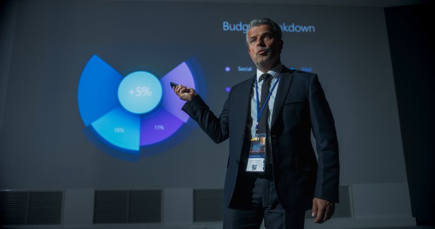 Low Angle Shot of Male CEO Giving Presentation to Diverse Audience of Businesspeople At International Business Conference.