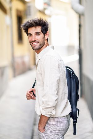 Man smiling while walking through the streets of Granada with backpack