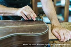 Male hands shaving back of guitar in luthier workshop 5QNxE4