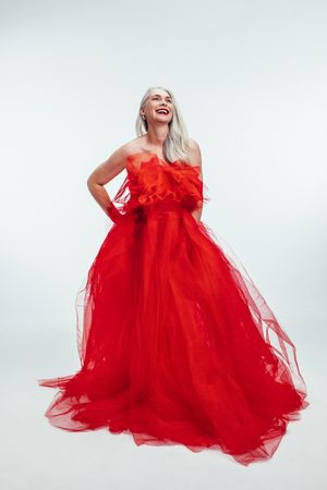 Beautiful adult woman wearing red gown in light studio