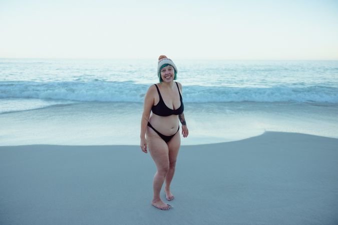 Full length shot of carefree swimmer  smiling at the camera while standing alone at the beach