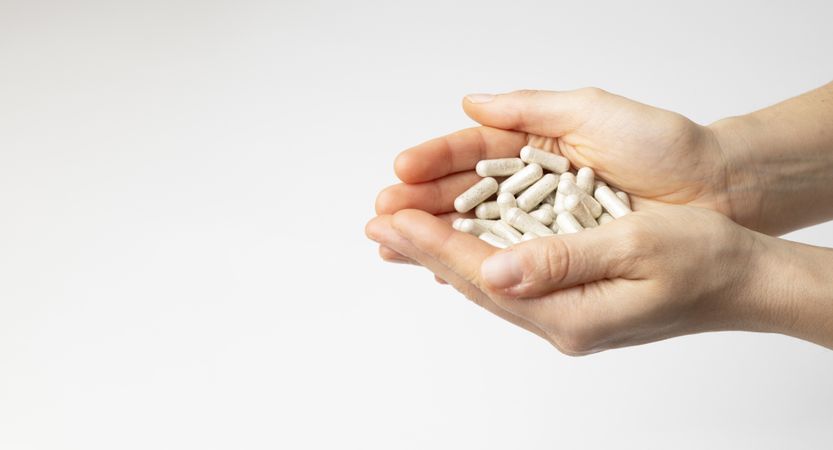 The hands of a woman hold a lot of multivitamin capsules, food supplement