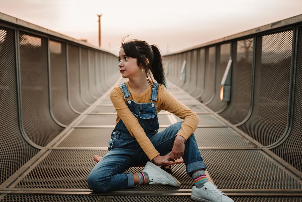Girl sitting on skateboard on walkway