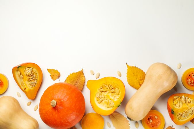 Composition with pumpkin, seeds and leaves on neutral background