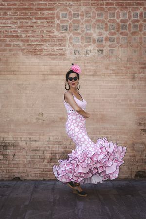 Passionate woman in flamenco dress dancing on street