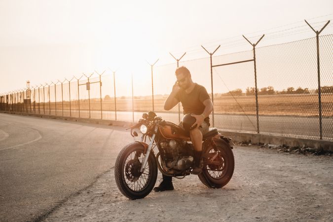 Man sitting on motorcycle and surfing mobile