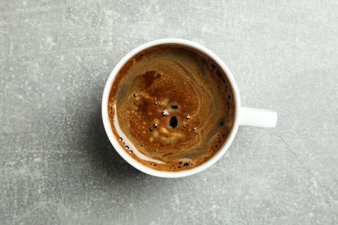 Cup of coffee on grey background, space for text