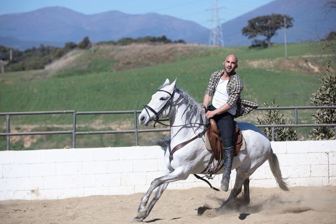 Happy man in checkered shirt galloping on horse