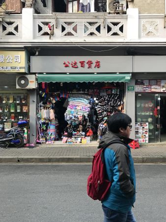 Side view of man with backpack walking on sidewalk in Shanghai Shi, China