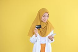 Asian Young Muslim Female Holding Credit Card and Mobile Phone