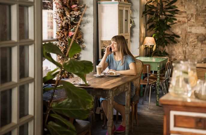 Cheerful woman talking on phone in cafe