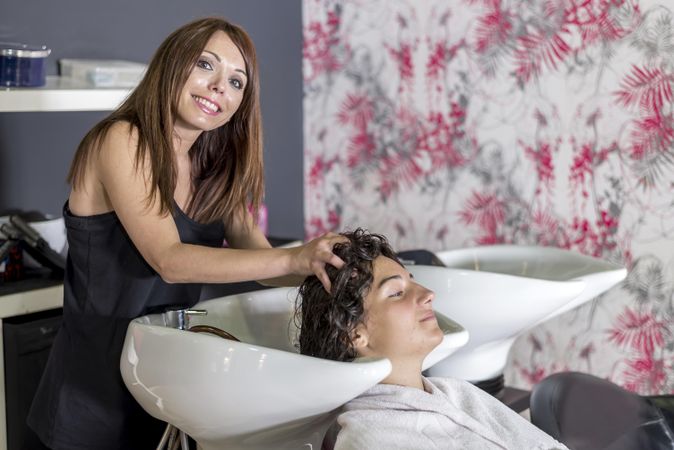 Hair stylist massaging head of client in sink