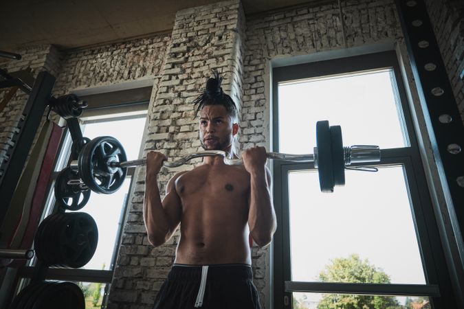 Black man exercising with barbell in gym