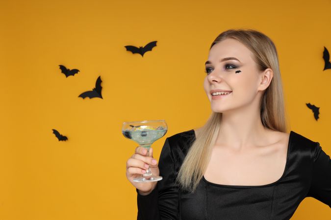 A woman at a party in the style of Halloween with a cocktail in her hands