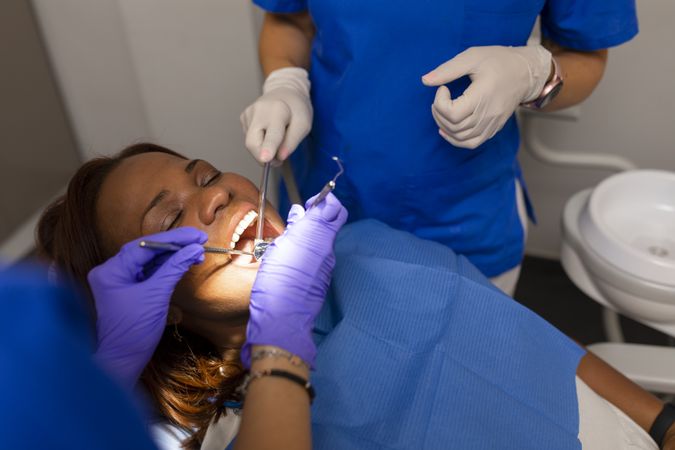 Black female dental patient lying back with open mouth during exam