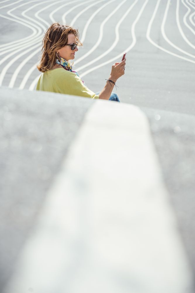 Modern relaxed woman on marked road and browsing smartphone