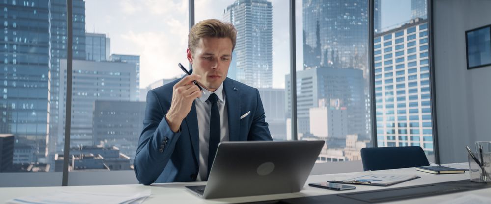 Confident Businessman in a Suit Sitting at a Desk in Modern Office