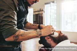 Barber applying shaving cream to male customer 0L3xRb