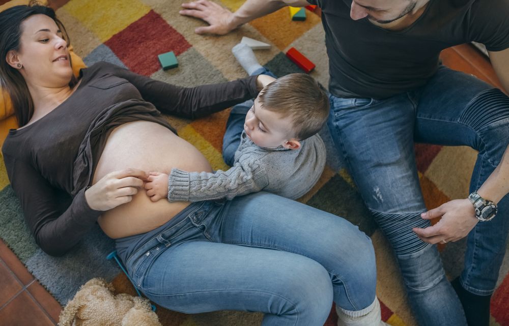 Toddler caressing belly of his pregnant mother