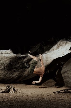 Man practicing rock climbing among large rocks in a forest