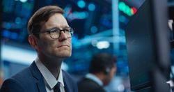 Professional Using Computer with Multiple Screens, Monitoring Financial Markets, Communicating with Business Partners.