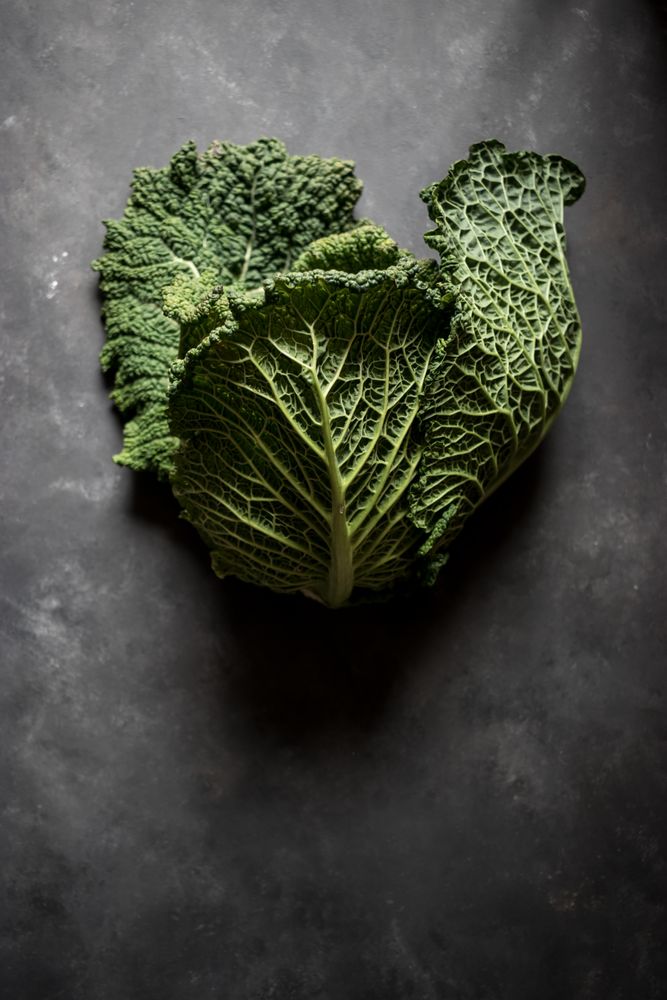 Woman holding fresh cabbage on table