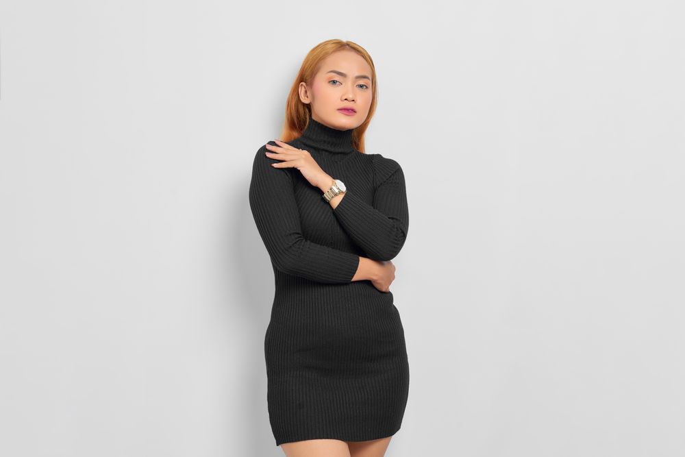 Sultry Asian woman with red hair in dark dress in studio shoot