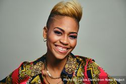 Portrait of joyful Black woman with short blonde hair in bold patterned shirt 0gdl35