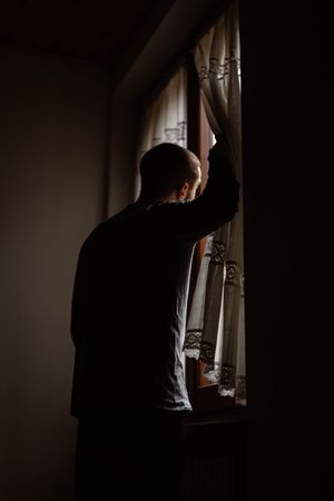 Male in casual wear standing by a window