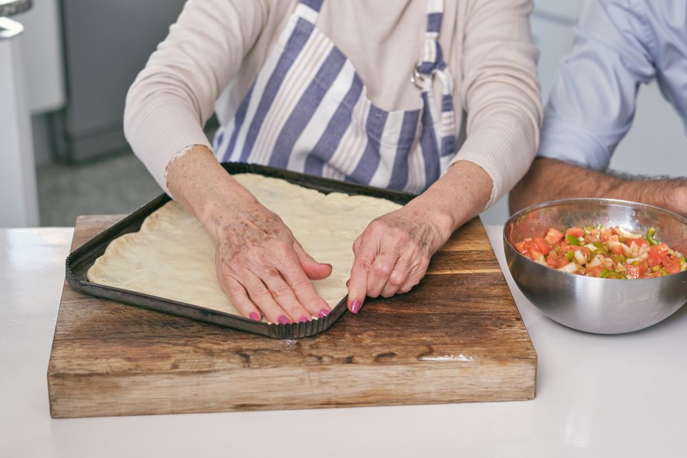 Anonymous woman preparing dough on baking pan