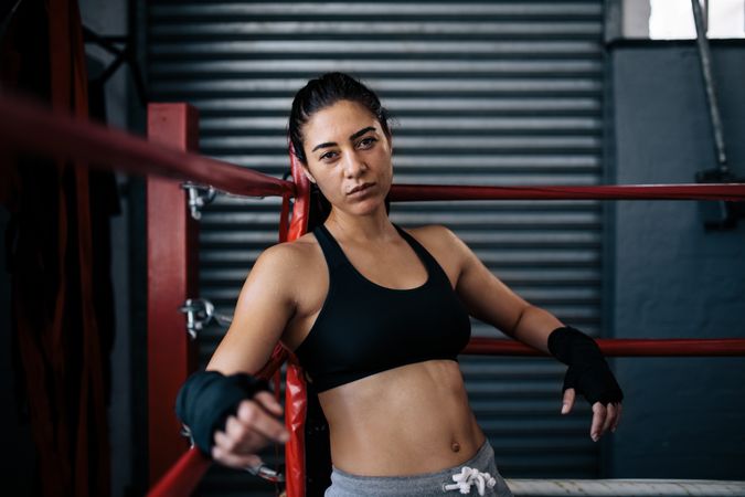 Fit female boxer leaning on the boxing ring