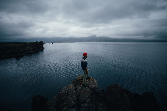 Man standing on edge of cliff on overcast day, landscape
