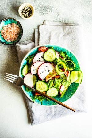 Teal bowl of healthy vegetable salad on rustic background
