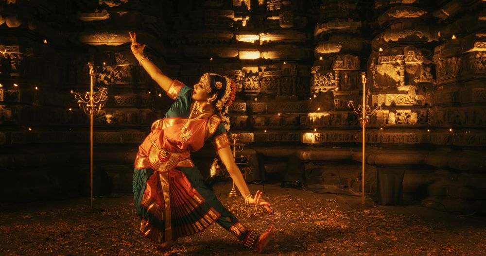 Portrait of Young Energetic Indian Woman Performing Traditional Folk Dance Inside a Candle-Lit Temple.