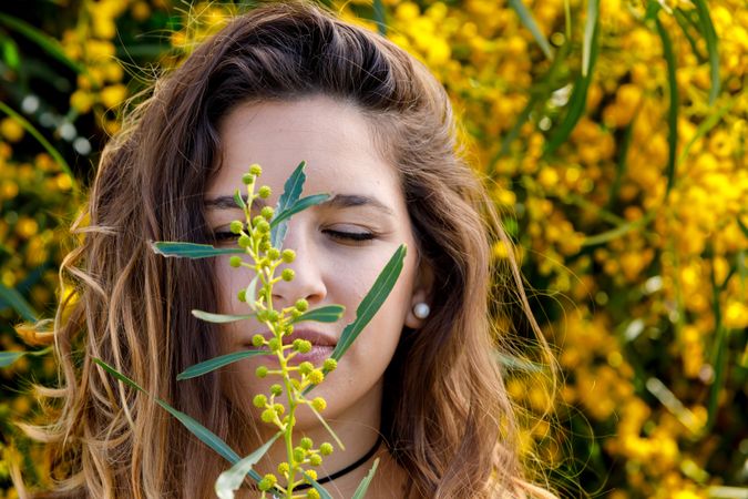 Young woman smelling flower from garden bush