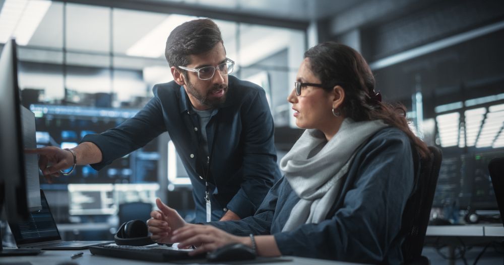 Two Diverse Multiethnic Indian Colleagues Having a Conversation While Busy Working on a Software Development Project.