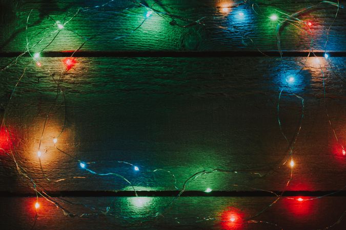 Multi-colored Christmas tree lights decoration on bright wooden background