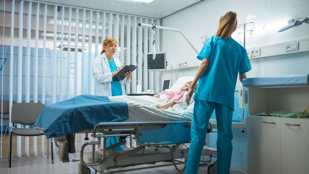 Sick Little Girl Lies on a Bed In the Hospital, Friendly Doctor Writes Medical Record