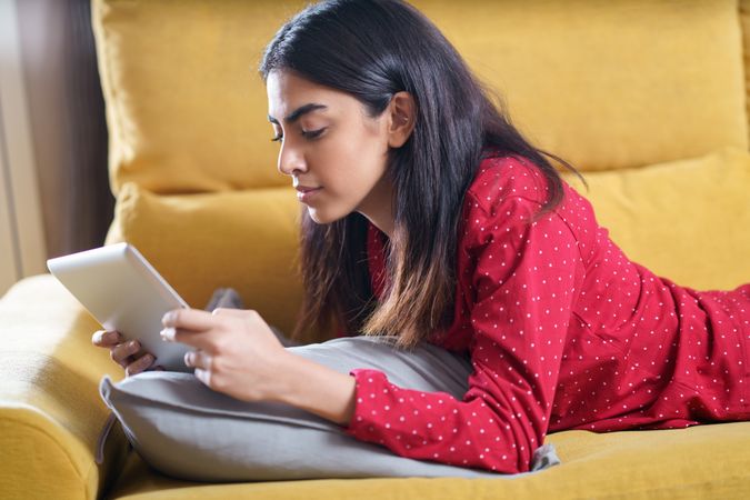 Female relaxing at home and reading something on a tablet