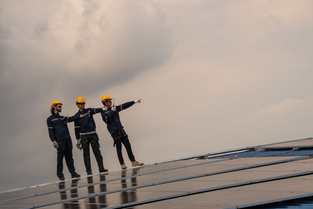 Engineer team checking solar cell  or photovoltaic cell installed on the roof of the factory. Technician worker repair or inspect the system. Industrial renewable energy concept